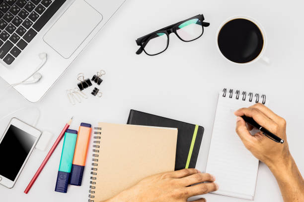istock Hand typing or writing something about business on white office desk table with computer and workspace for office work. Top view with copy space 1201650744