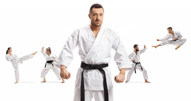 maestro di karate con cintura nera in piedi di fronte a uomini e donne che praticano arti marziali - extreme sports karate sport exercising foto e immagini stock