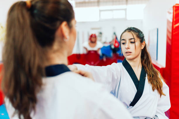 istock Two young women practice taekwondo in a training center 1201652454