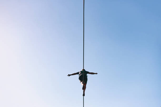Young Caucasian slackline man practicing slackline against the sky on a clear summer day