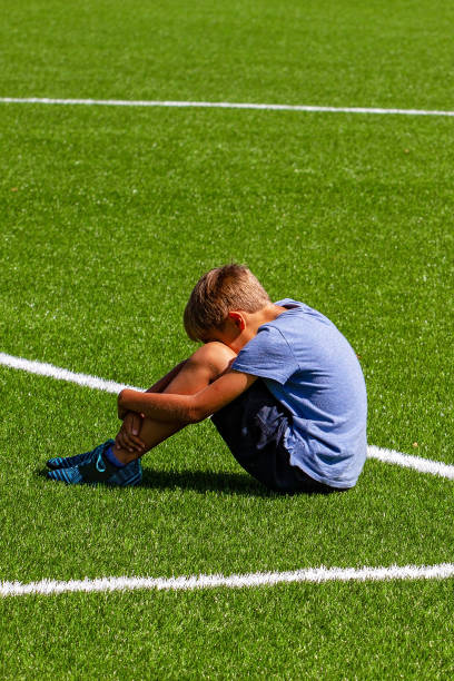 istock Sad disappointed boy sitting on the grass in stadium 1201652791