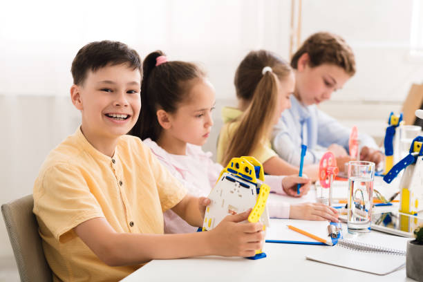istock Happy schoolboy showing his robot and smiling at stem lesson 1201654971