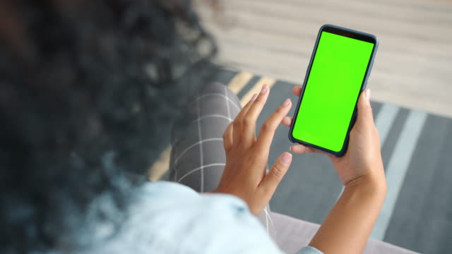Back view of woman brunette using green screen smartphone touching screen