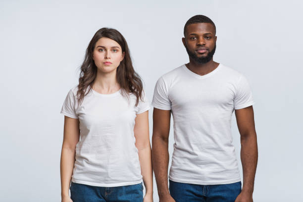 Interracial couple posing with serious face expressions over light background