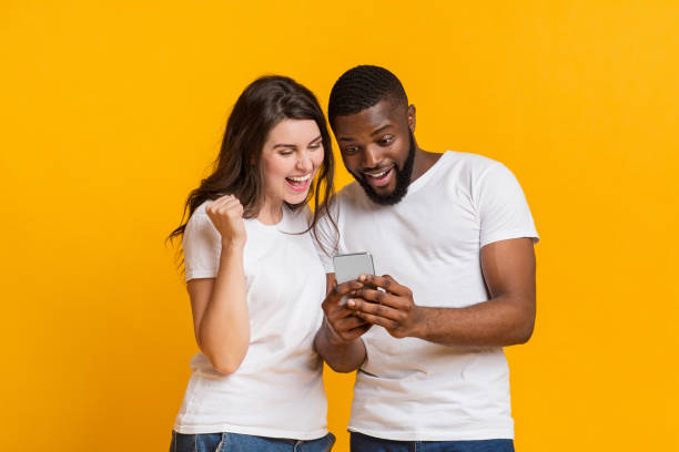 istock Surprised multiracial couple looking at smartphone screen and exclaiming with joy 1201655875
