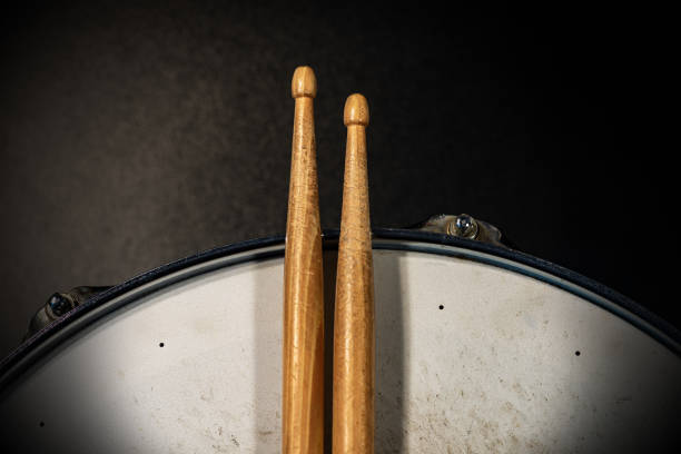 Two wooden drumsticks on an old snare drum - Percussion instrument Close-up of two wooden drumsticks on an old metallic snare drum with dark background. Percussion instrument snare drum photos stock pictures, royalty-free photos & images