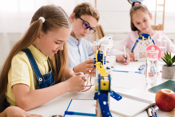 istock Schoolgirl making robot, working with wires in class 1201656763