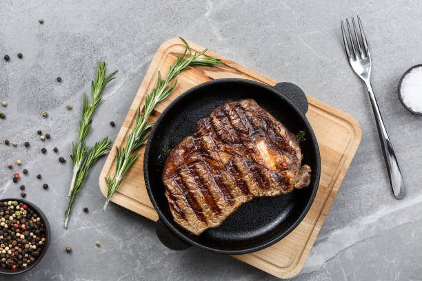istock fried steak in pan on gray marble table top view 1201656942