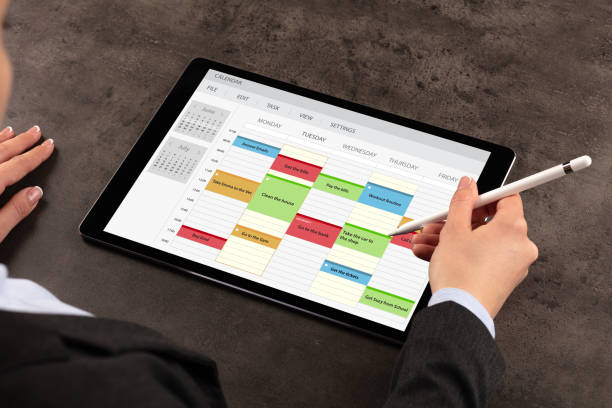 mulher de negócios agenda seu programa em tablet - mulher de negócios olhando tablet digital no calendário - fotografias e filmes do acervo