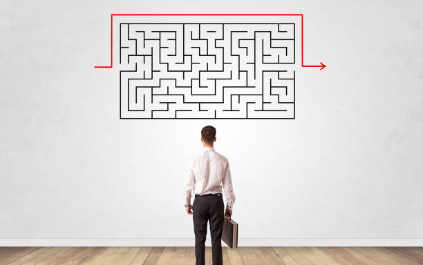 istock Businessman looking to a maze on a wall 1201658403
