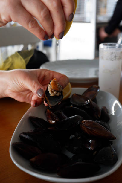 istock Woman's hand squeezing lemon to stuffed mussels. 1201658807