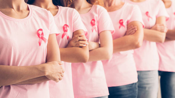 Unrecognizable Ladies In Cancer Awareness T-Shirts Posing Over White Background Oncology Prevention. Group Of Unrecognizable Multiracial Ladies In Pink Cancer Awareness T-Shirts Standing Posing Over White Background. Panorama, Shallow Depth cancer screening stock pictures, royalty-free photos & images