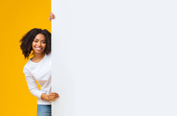 istock Cheerful afro woman holding big white advertisement board with free space 1201662087