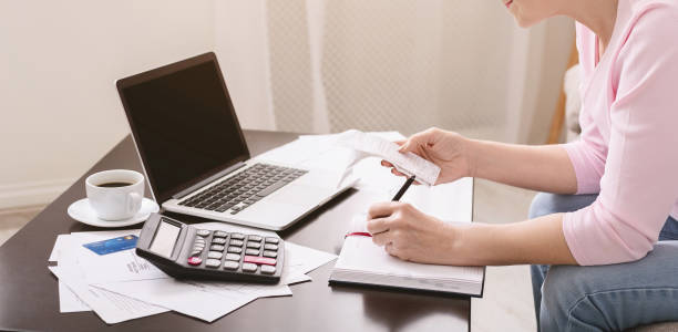 istock Senior lady writing calculation in notebook with bills 1201662143