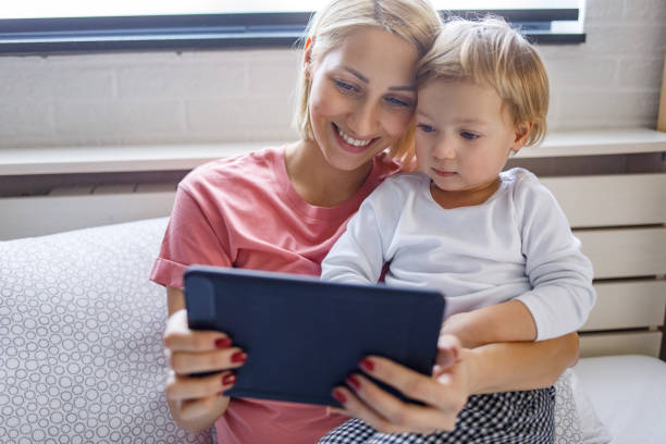 istock Happy young mother with daughter using digital tablet at home 1201662367