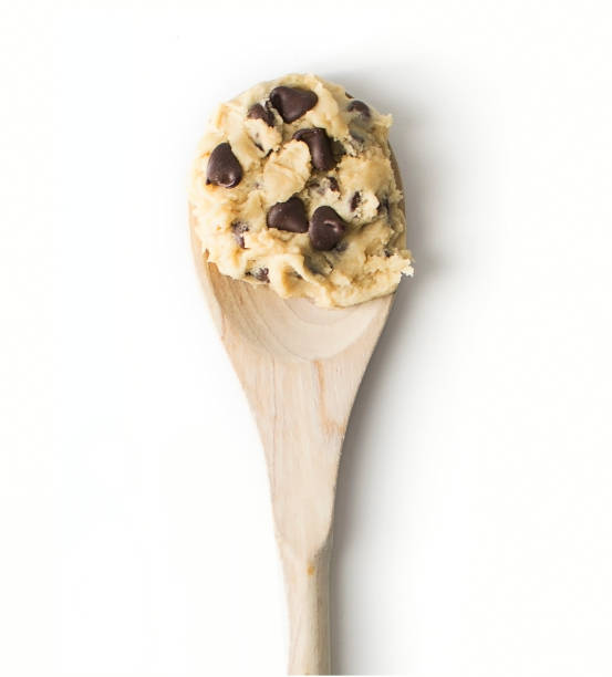 Chocolate chip cookie dough on a wooden spoon Raw cookie dough on a wooden spoon over a white background chocolate chip cookie stock pictures, royalty-free photos & images