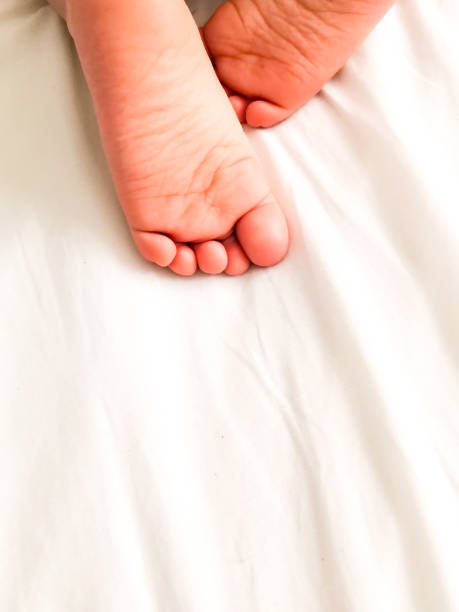 istock Little baby with cute feet on bed sheet, above view. Space for text 1201670196