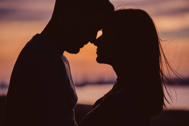 Silhouette of young couple having romantic moments against the sunset background stock photo