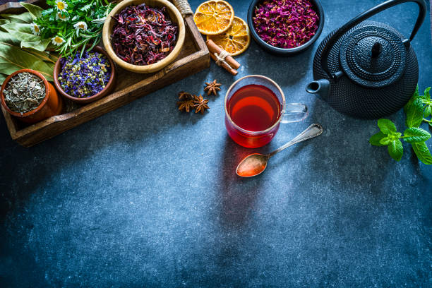 istock Tea cup with several dried tea leaves and flowers shot from above on bluish table. Copy space 1201672895