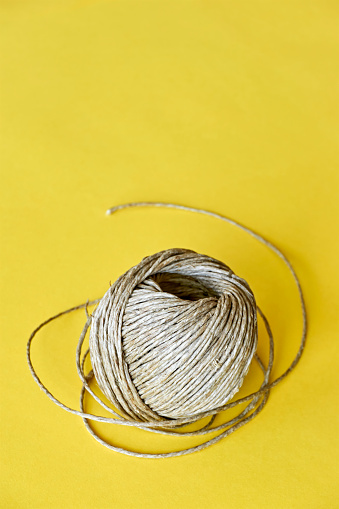 Roll of natural eco friendly hemp fiber, manila rope, sisal twine or sisal fibre on a yellow background. Vertical image with copy space.