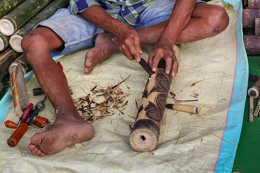 Indian craftsman working with a chisel to make craft items for home decor at a handicraft fare at Kolkata