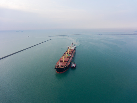 Aerial view of Oil tanker, gas tanker in transit. Logistics and transportation with working crane bridge in harbor