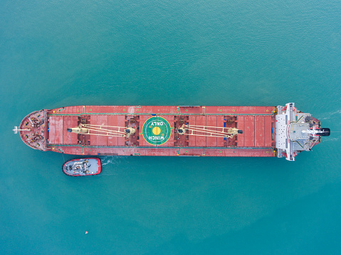 Aerial view of Oil tanker, gas tanker in transit. Logistics and transportation with working crane bridge in harbor