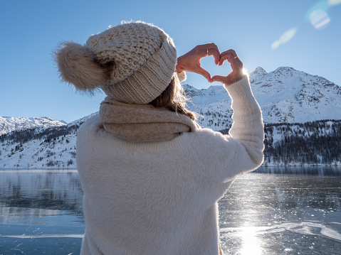 Young woman ice skating on frozen lake and making a heart with hands. winter vacations