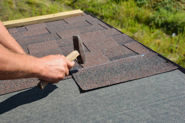 istock Roofer installing asphalt shingles on house roofing construction with hammer and nails in action. 1201683737