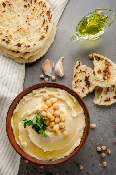 istock Flat lay view at hummus topped with chickpeas and green coriander leaves on stone table served with traditional Pita bread 1201683953