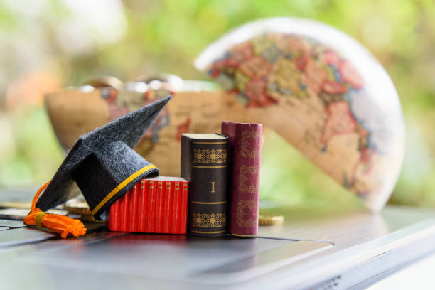 istock Graduate study abroad program for opening vision or expand world view concept : Graduation cap or hat, world globe map, foreign text book on laptop, depicts achievement or success in online education. 1201686295