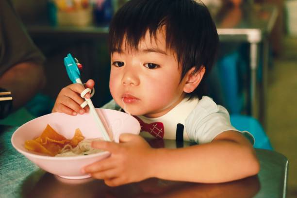 istock Little boy eating noodles 1201686304