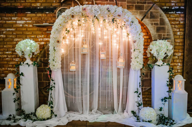 Wedding ceremony with a vintage candles. Arch for wedding area a is decorated with white flowers and greenery. Wedding ceremony with a vintage candles. Arch for wedding area a is decorated with white flowers and greenery. wedding hall stock pictures, royalty-free photos & images