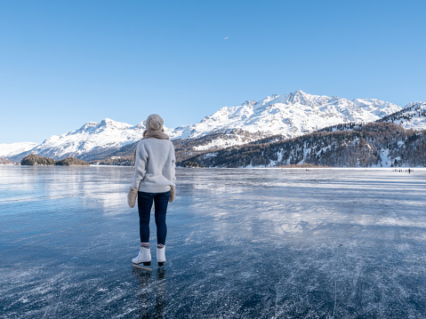 Young woman ice skating on frozen lake at sunset having fun and enjoying winter vacations