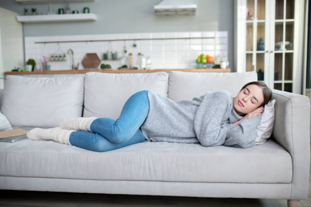 istock Young girl in a grey sweater having a nap on a sofa 1201694973