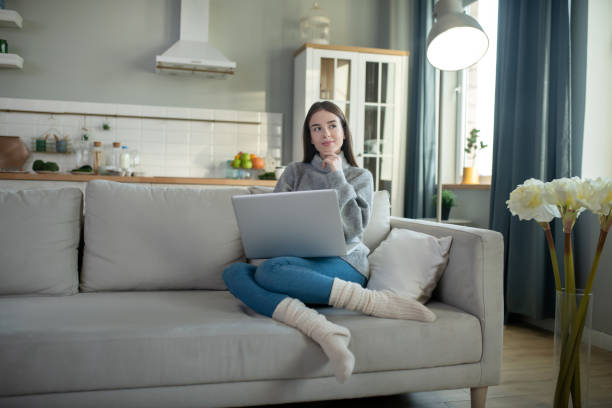 istock Young girl in a grey sweater working remotely 1201695026