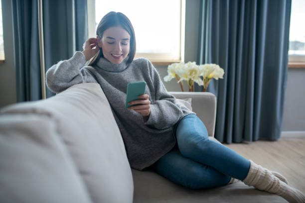 istock Dark-haired girl in a grey sweater reading a message 1201695343
