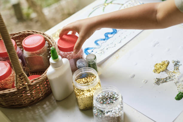 istock Boy's hand picking up jar of glitter for making art work 1201695538