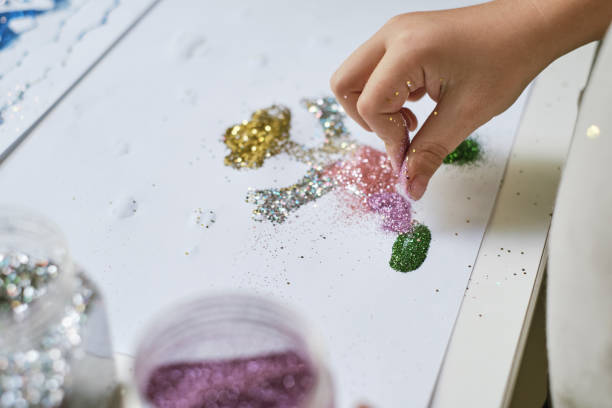 istock Child's hand making funny art work with glitter 1201697206