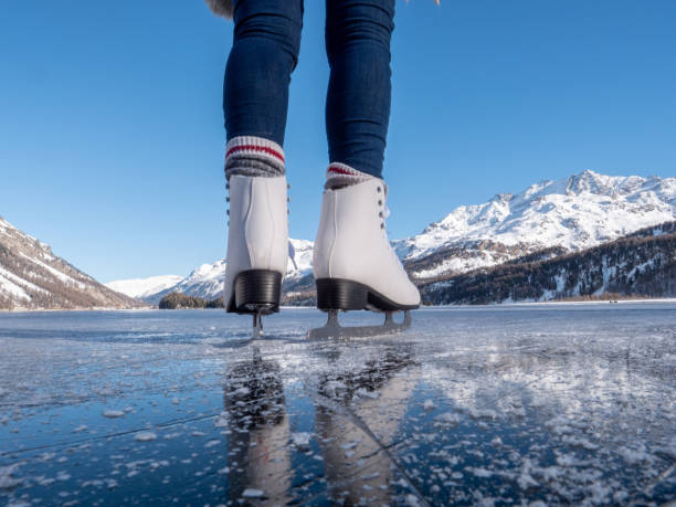 Close up on feet in ice skates on frozen lake at sunset Close up on woman's feet in ice skates standing on frozen lake at sunset,  winter holidays concept. graubunden canton stock pictures, royalty-free photos & images