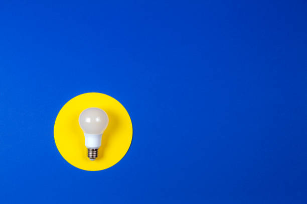 istock One light lamp bulb on yellow and navy blue background 1201698890