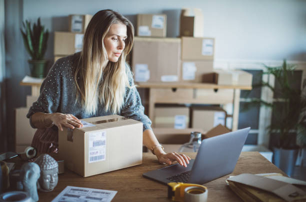 Help of technology in delivery business Working woman at online shop. She wearing casual clothing and checking on laptop address of customer and package information market vendor stock pictures, royalty-free photos & images