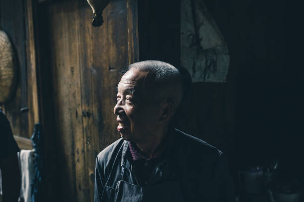 portrait of chinese senior man in old wooden barn in daxu ancient town