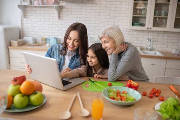 mama córka babcia oglądania przepisów online w laptopie. - grandparent using computer laptop dining table zdjęcia i obrazy z banku zdjęć