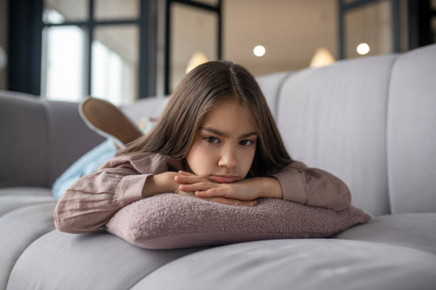 istock Little girl with a sad look lying on the couch. 1201703689