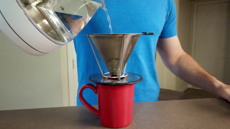 White male model, demonstrates a pour over coffee maker at home, blue shirt anonymous, low angle 4k.