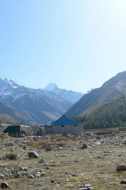 A mountain Alpine hut cabin in high Himalayas mountains, located to provide shelter to mountaineers, climbers and hikers. An interlocking overlapping spur hill ridges V-shaped valley in background.