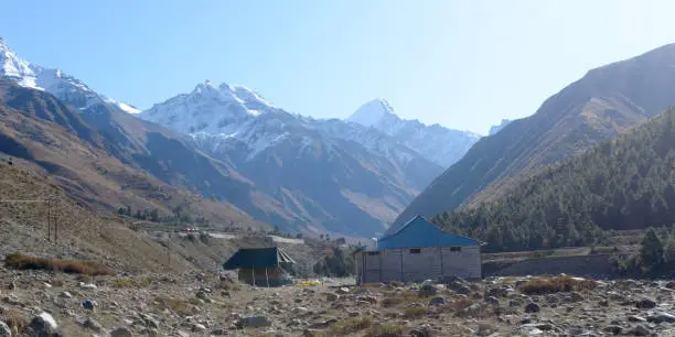 A mountain Alpine hut cabin in high Himalayas mountains, located to provide shelter to mountaineers, climbers and hikers. An interlocking overlapping spur hill ridges V-shaped valley in background.