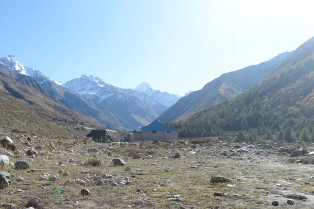 A mountain Alpine hut cabin in high Himalayas mountains, located to provide shelter to mountaineers, climbers and hikers. An interlocking overlapping spur hill ridges V-shaped valley in background.