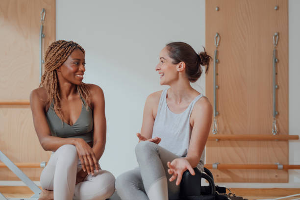 istock Two Women Sitting on Pilates Reformer 1201708187